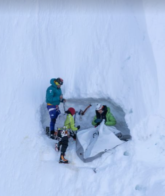 The climbers in an ice niche they carved on the vertical snow