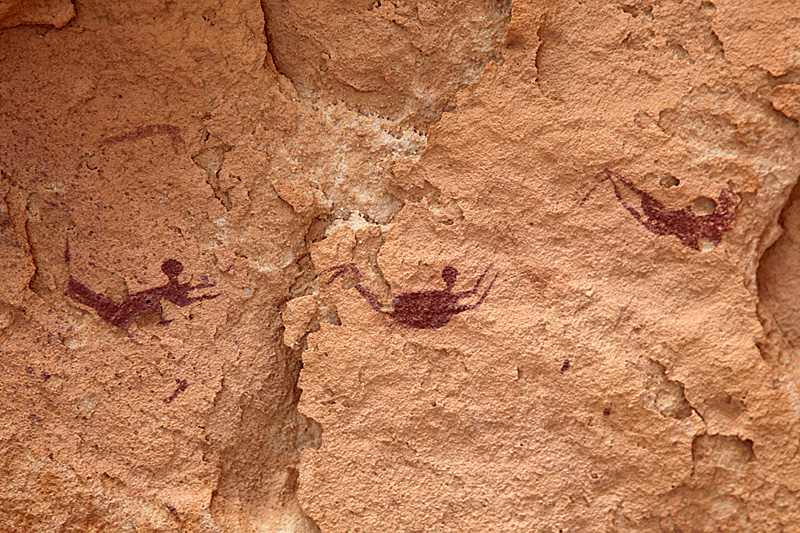 Three figures drawn as if doing breast stroke swim across the rock.