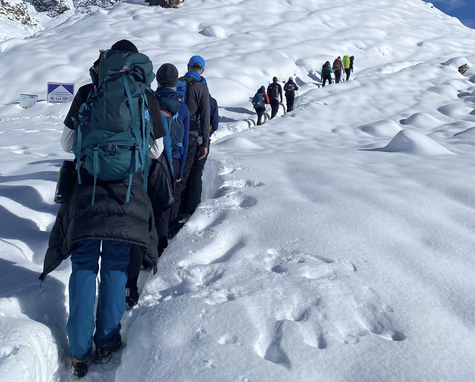 A line of trekkers on a snowed-up trail