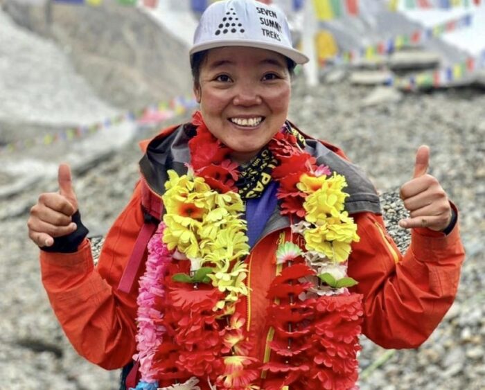 He Jing smiles and gives thumbs up, adorned with garlands in Base Camp