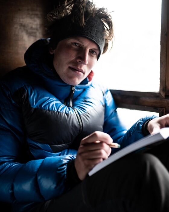 Kobusch taking notes in a diary, sitting by a window