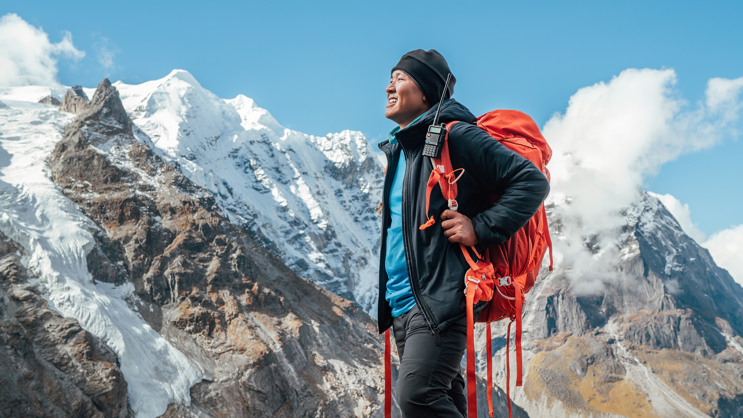 a Tibetan man walks with a pack in the mountains