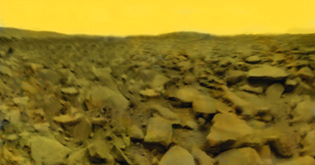 A yellow sky over a plane of rocky moraine.