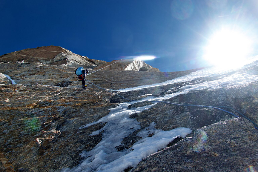 A climber rappels down a vertical face.