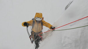 A climber on a traverse on snow in a whiteout