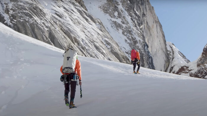 two men hike through the snow