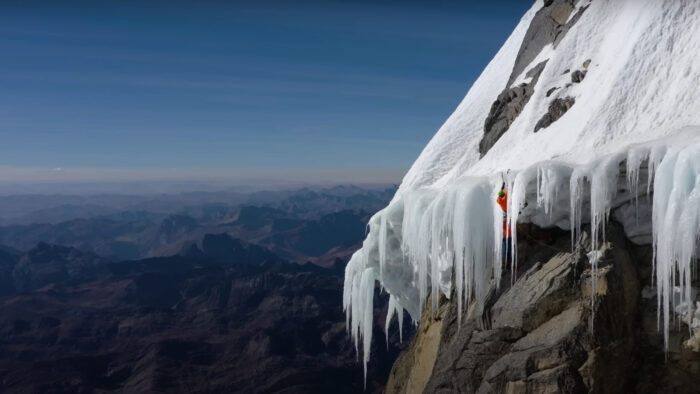 a man climbs up over an ice roof