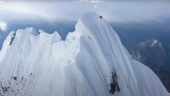 two tiny figures sit on the summit of a beautiful mountain