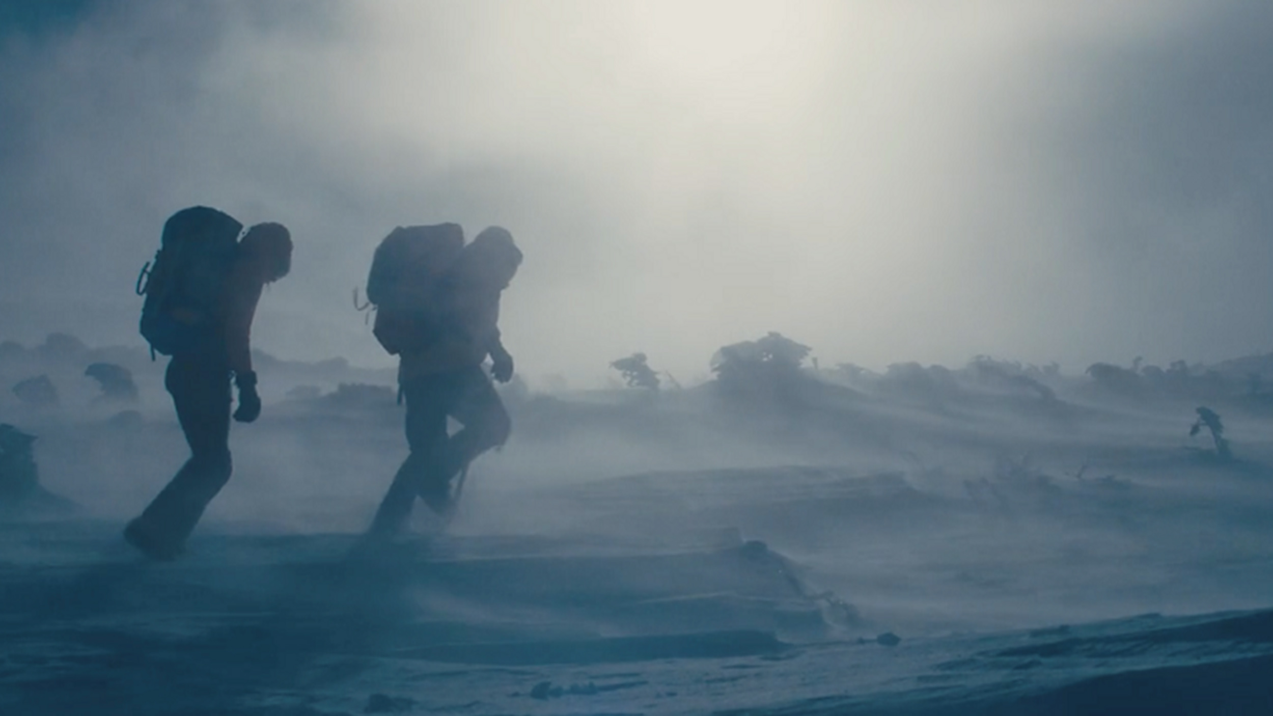 two men trek across a snowy landscape