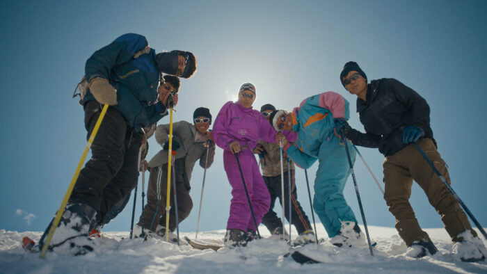 a group of young skiers look down at the camera