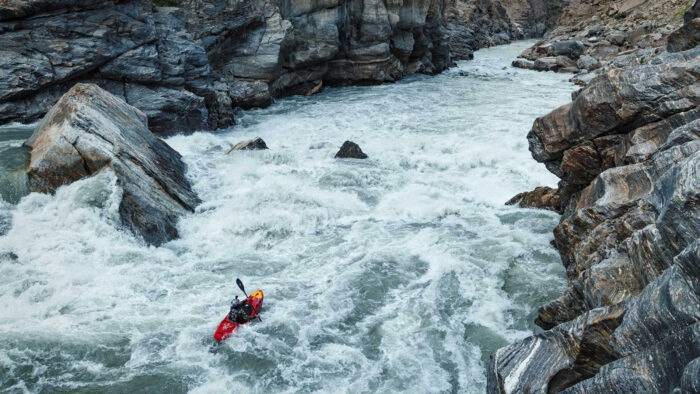 a woman kayaks down whitewater in a gorge