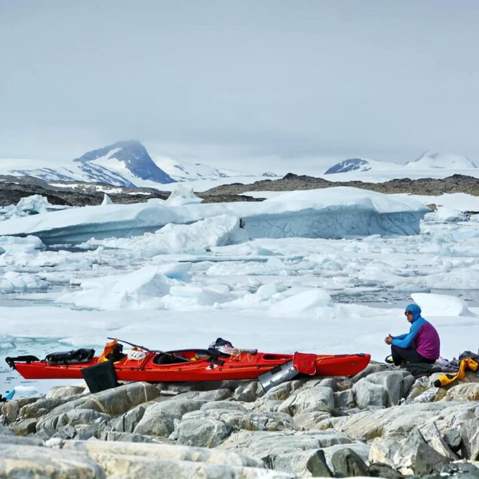 A climber by its Kayak, packed ice behind him