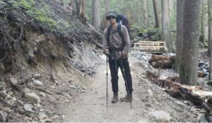 young hiker in sunglasses on wooded trail