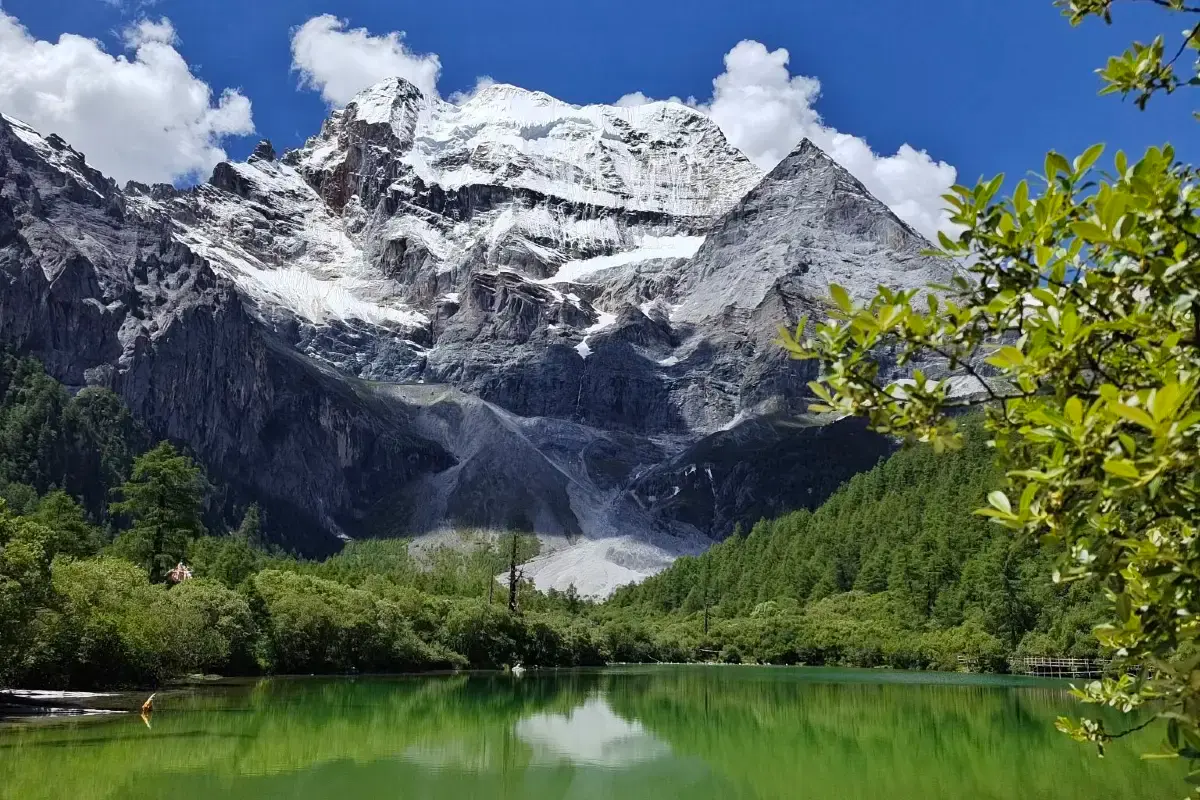 Mountains rise over a green lake.