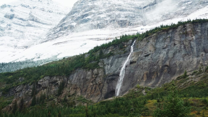 a waterfall with mountains in the background