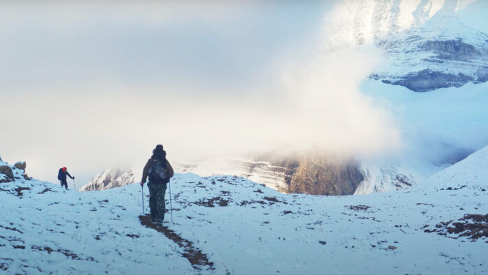 two people walk over a snowy pass