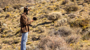 a man stands in a desert holding a microphone