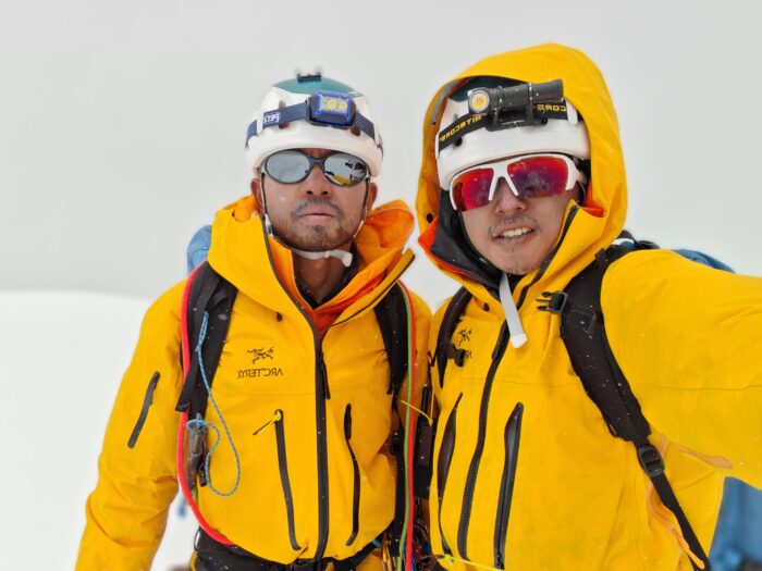 The climbers on a snowy summit in a foggy day