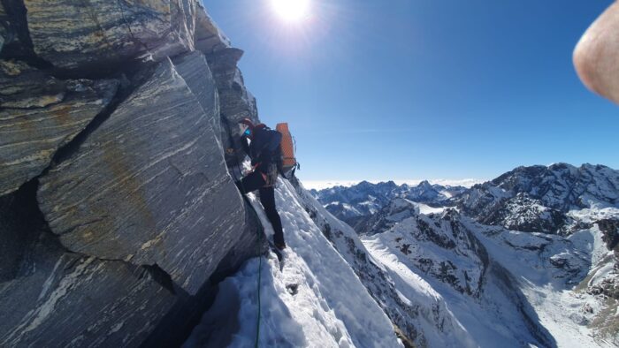 A climber between steep snow and a rocky band. 