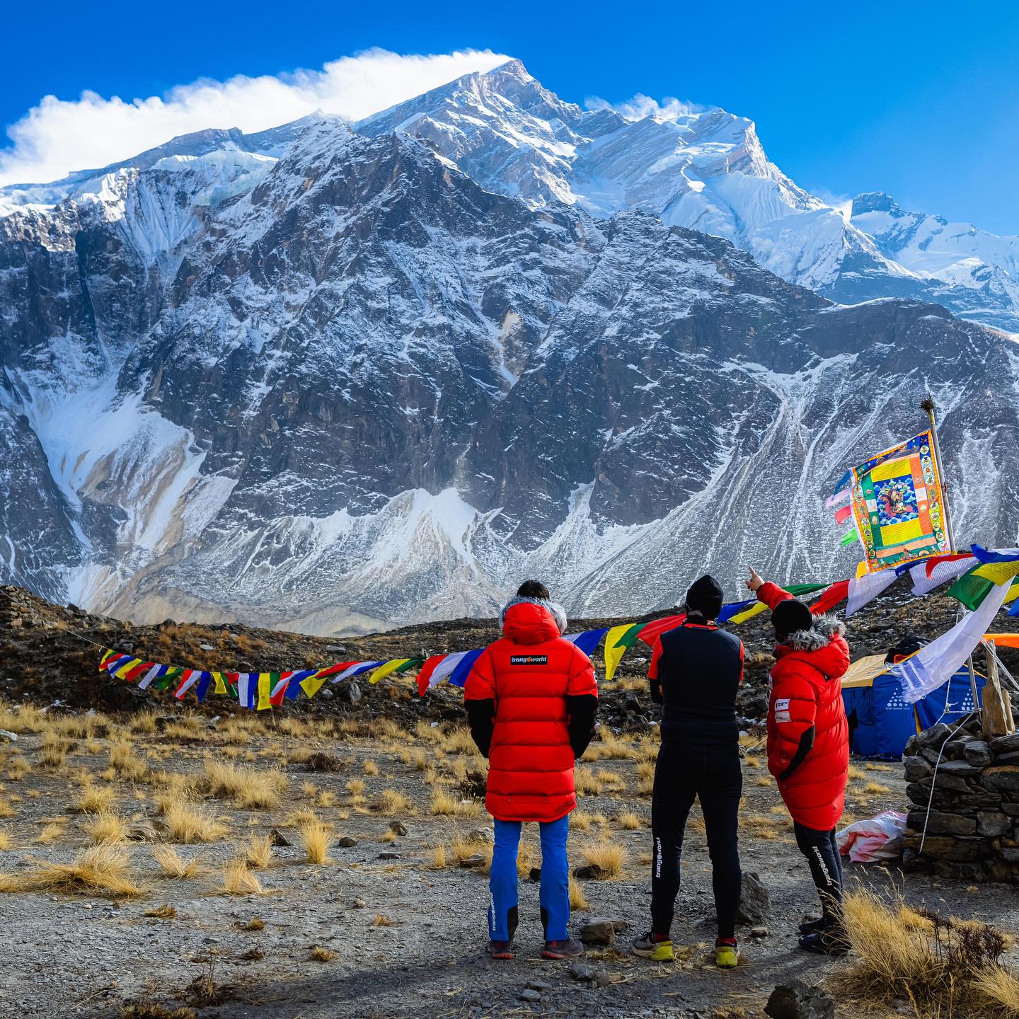 Three climbers by a chorten looking to Annapurna in front of them.