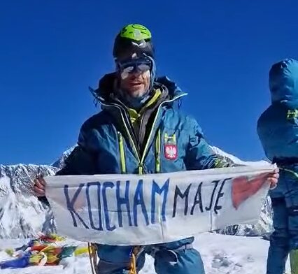 Waldemar Kowalewski with a dawn suit and a helmet on top of the hood, on the summit of Ama Dablam. 