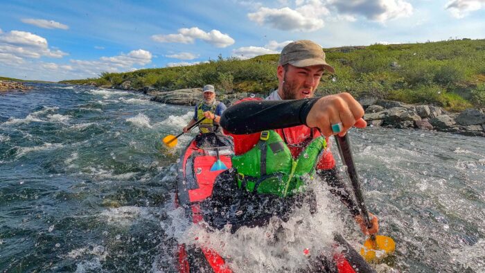 two men paddle a canoe