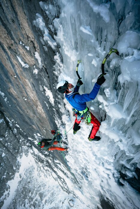 The climber on an ice section, his partner belays him from below