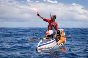 man in kayak holding lit flares