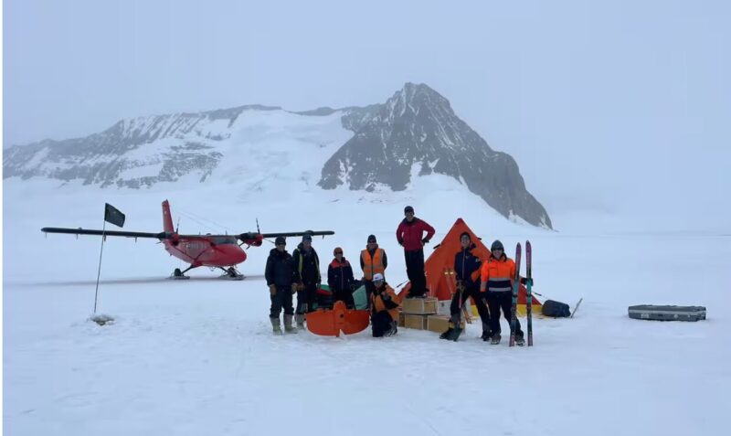 scientists in Antarctica beside Twin Otter airplane