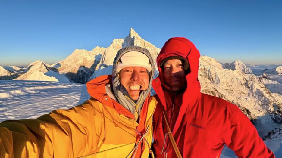 selfie of two climbs, one in yellow, one in red, on a summit