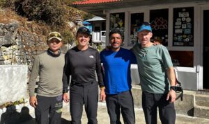 The climbers pose with light shirts in a sunny day by a lodge.