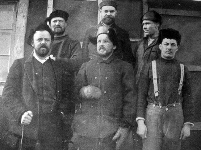 a group of men in front of a hut