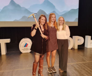 The women climbing team on a stage, Olga Lukashenko holds a golden ice axe