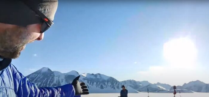 a man points at the sun in Antarctica