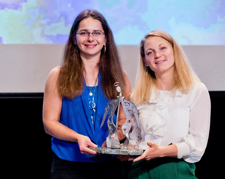 two women receive climbing award, hold trophy