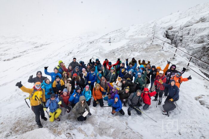 A group poses for a photo on snowy terrain. 