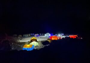 A group of colorful tents lit up in the pitch black night.