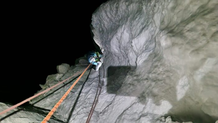 A climber on fixed ropes at a vertical snow/ice section. 