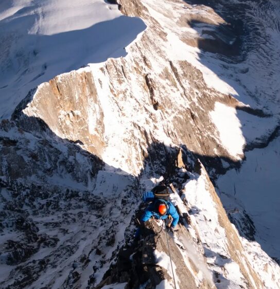 A climber on a sharp ridge on mixed terrain 