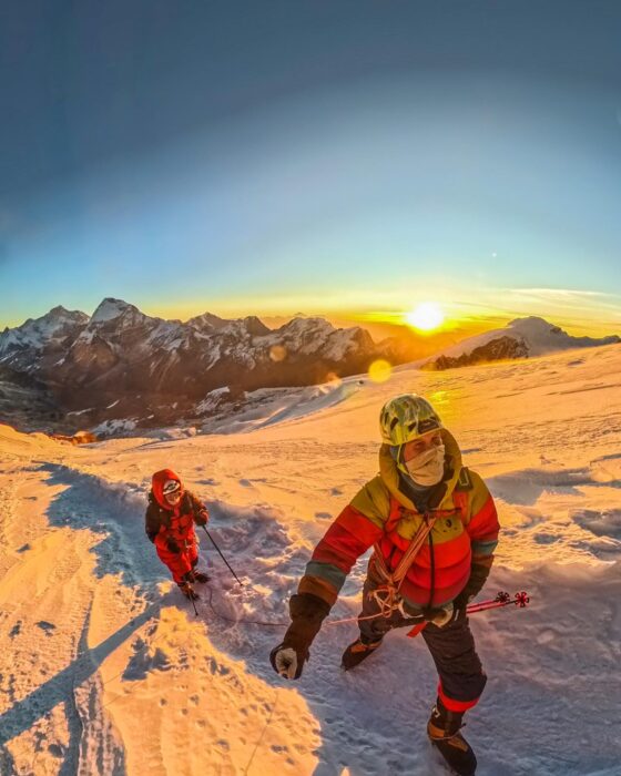 The climbers at sunrise on a snowy slope. 