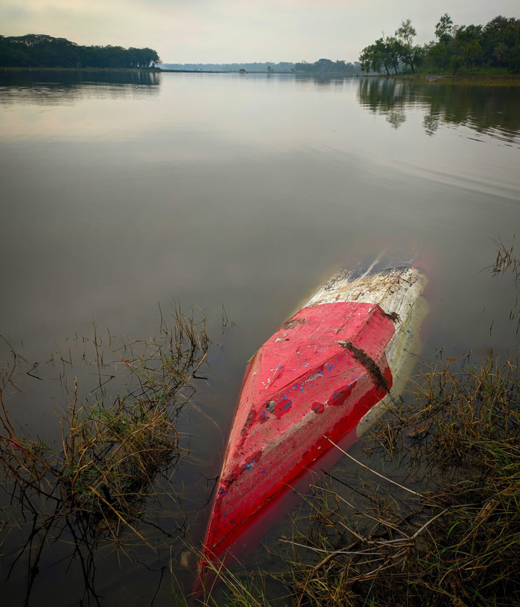 an overturned kayak floating by the edge of a lake