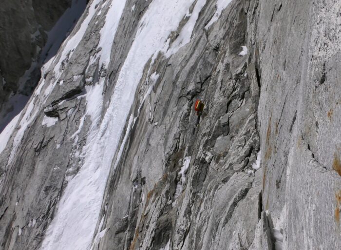 The bivy tent hanging on a mainly rocky, vertical face.