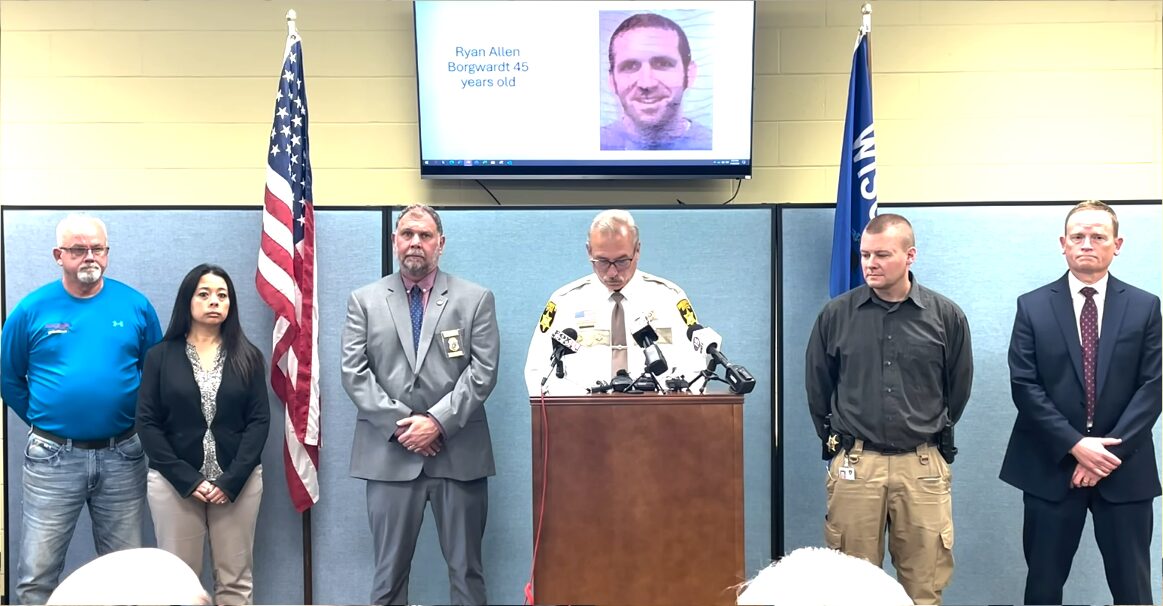 Six people standing in the sheriffs office giving a press conference