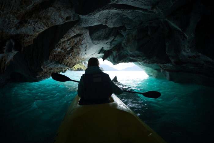 a woman kayaks inside a marble cave