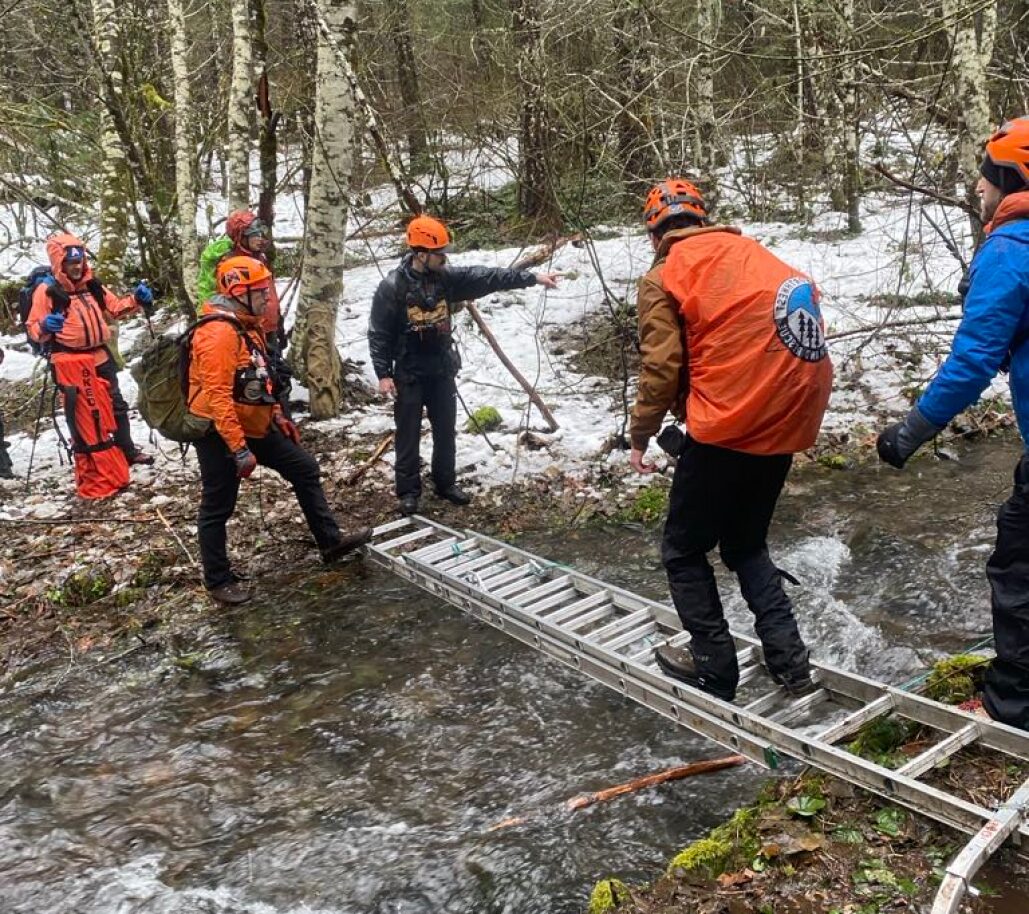 a group of volunteers crossing a muddy stream