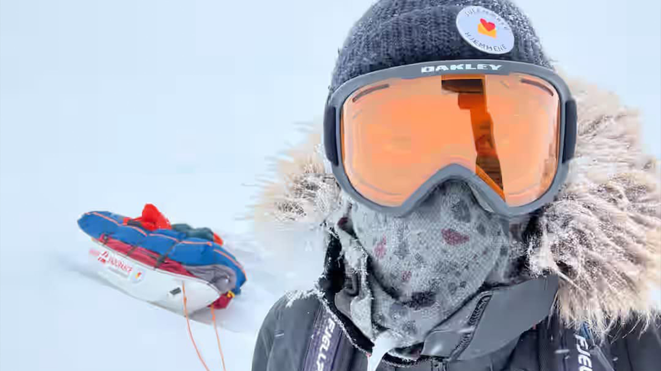 a man in ski goggles and a jacket takes a selfie in front of a sled