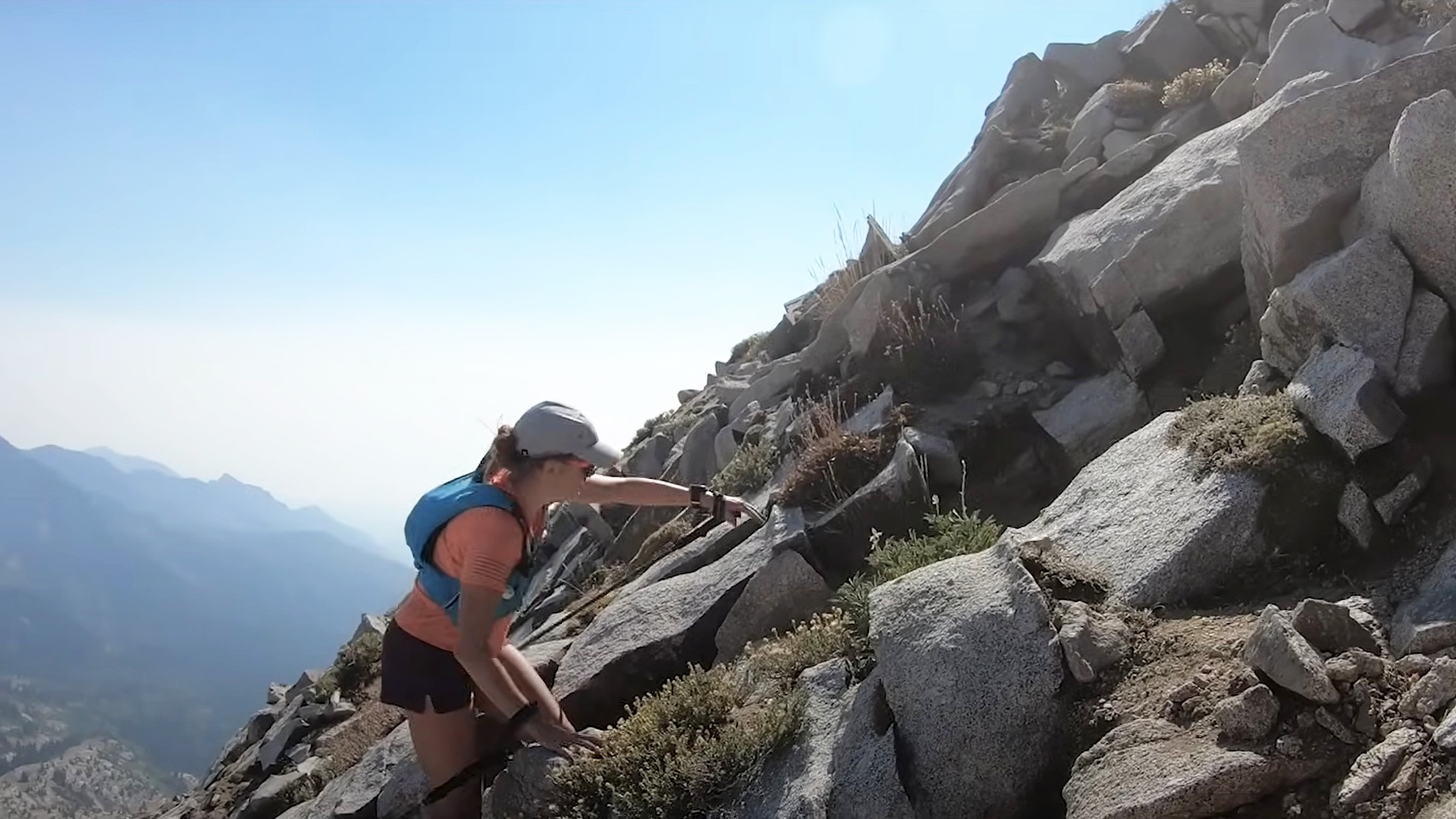 a woman scrambles up a ridgeline