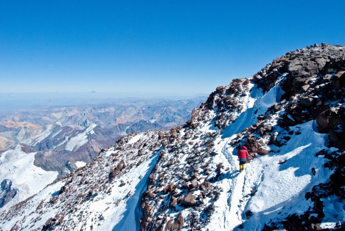 A climber on a lightly snow-covered trail aproaching the summit of Aconcagua