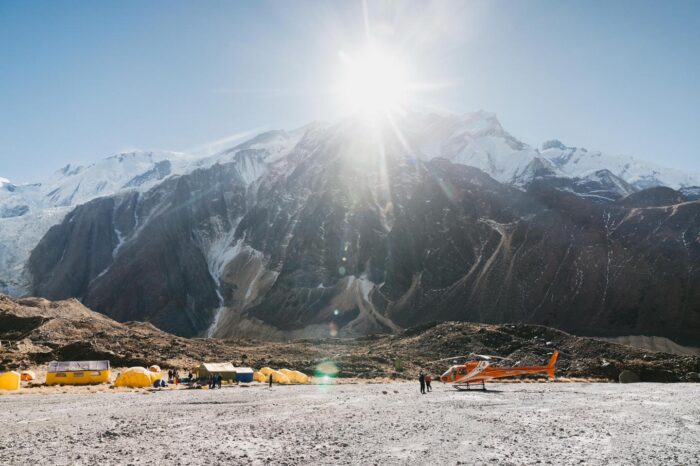 Some tents on an icy surface at the base of a very dry Annapurna