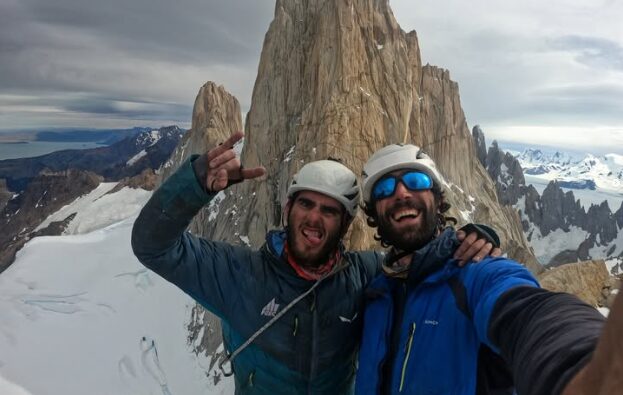 Two climbers greet with a Patagonian granite spire behind